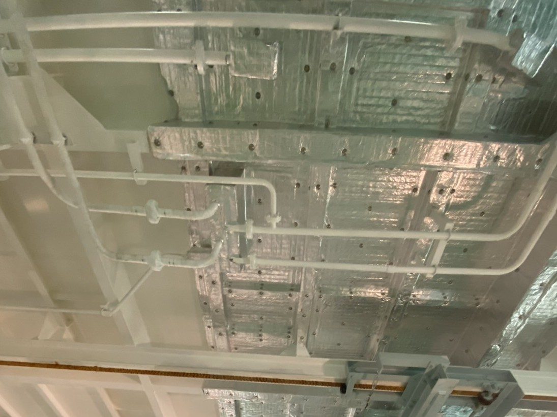 配管の奥の天井に、ピンで留めた銀色の断熱材が張られている